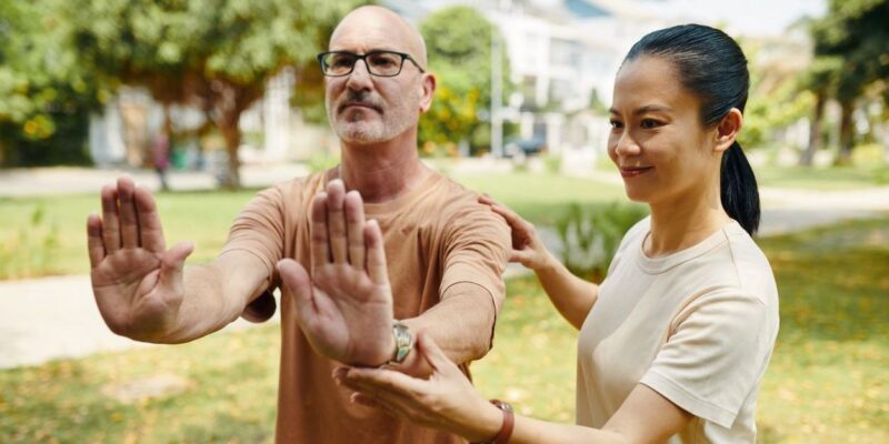 woman helping man with tai chi poses for mental health