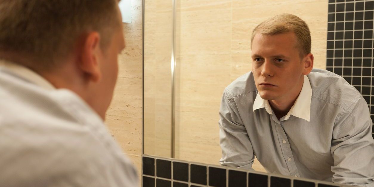man looking in mirror who appears hungover